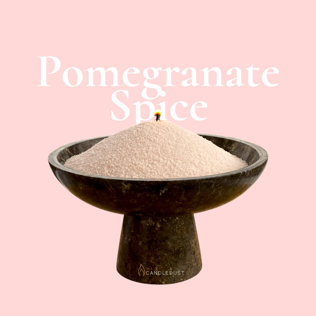 Pomegranate Spice text on a matching rich spiced red background with a glass vase full of unlit pearled candle sand in the foreground