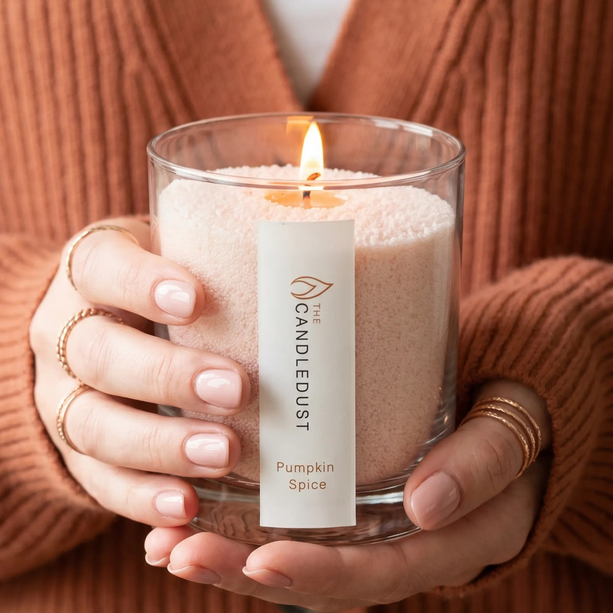 Woman holds Lit Candledust Pumpkin Spice scented pearled candle in a 160g glass jar in hands 