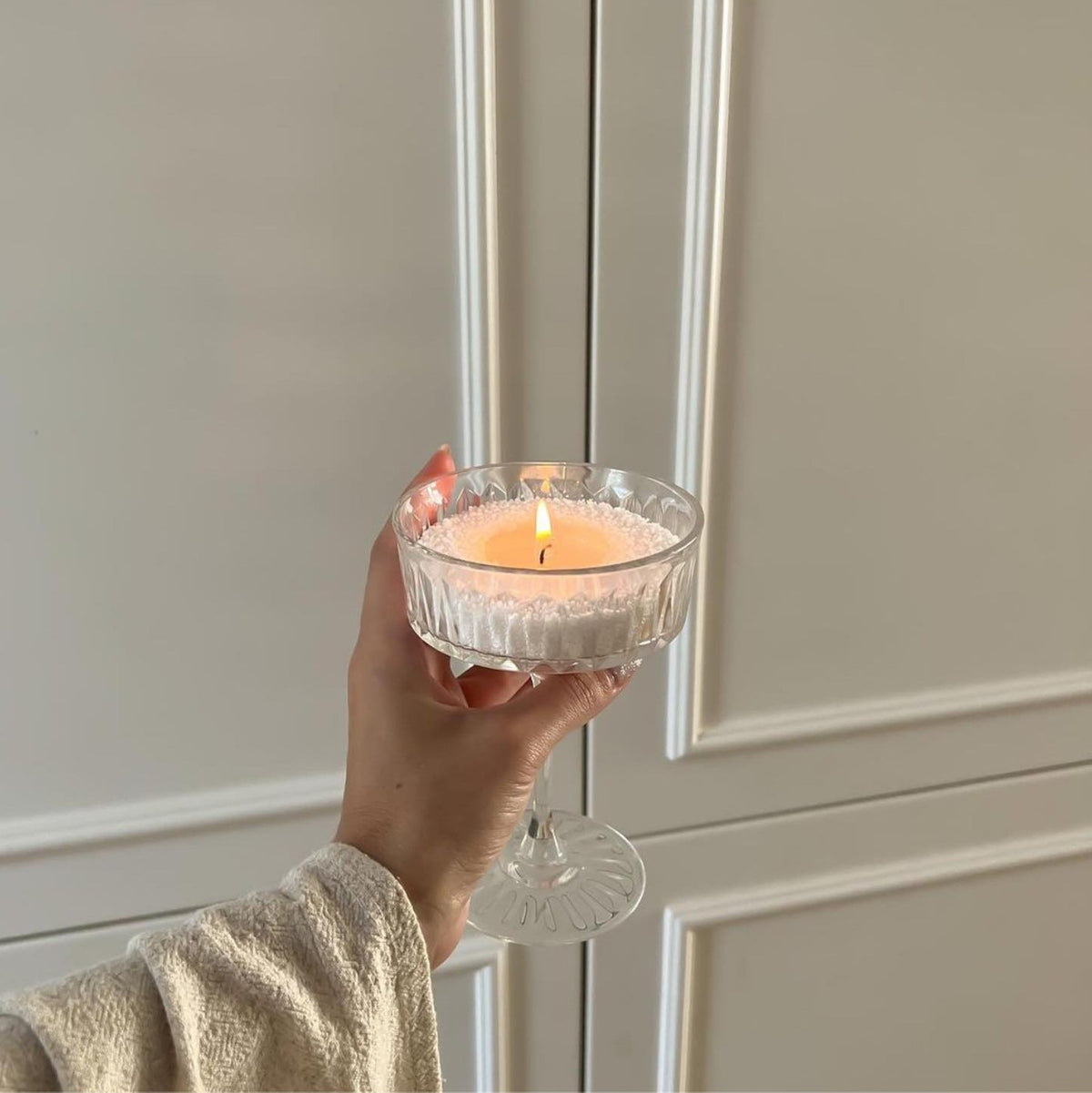 Woman holds an elegant glass candle filled of Pumpkin Spice scented pearled candle sand
