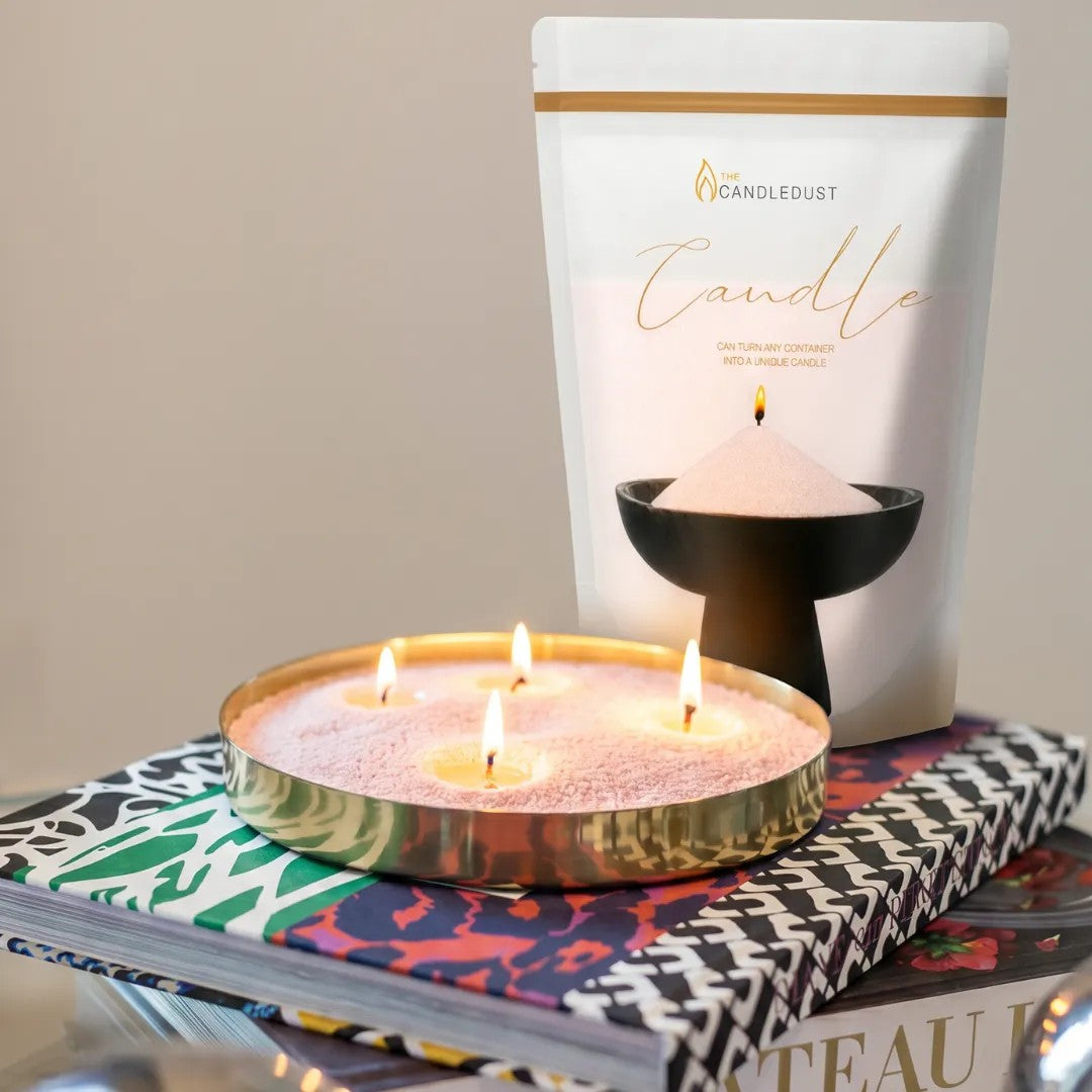 Lit Pumpkin Spice scented pearled sand candle displayed on a decorative tray resting on stacked books
