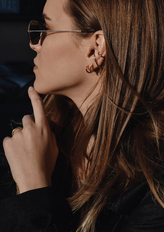 Model styling the minimalist gold Radius Earrings with a sophisticated outfit.