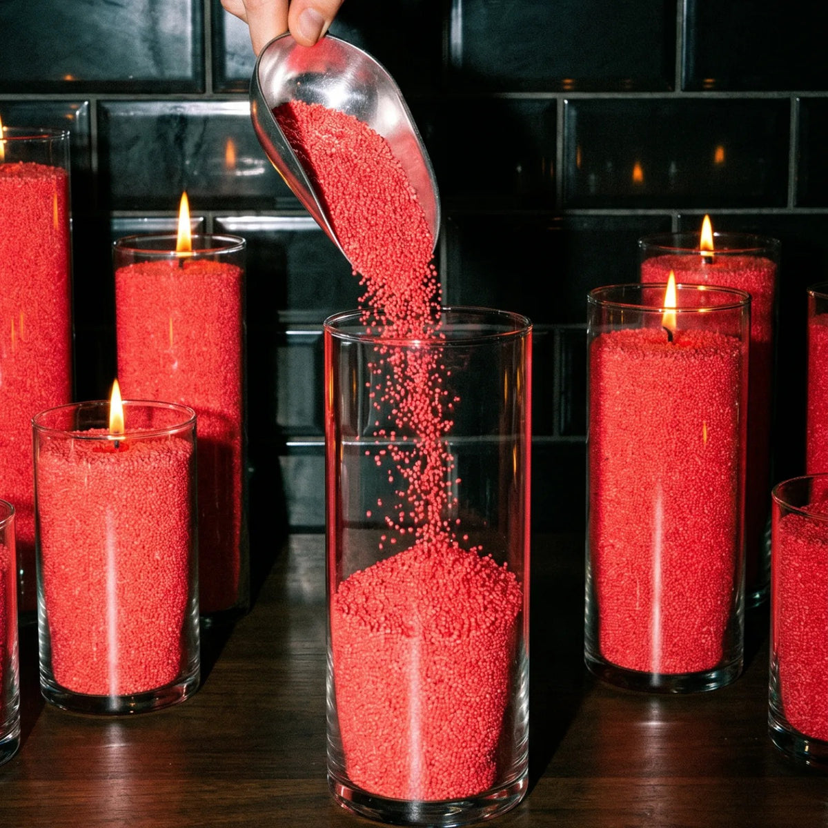 Close up of  filling up  decorative glass candle holders with Red natural pearled candle sand