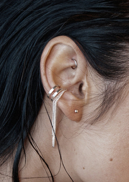 Close-up of a model's ear wearing the stylish no-piercing silver Revolve Ear Cuff.