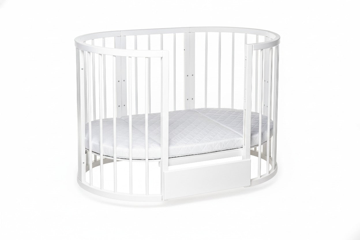 Ergonomic round baby mattress fitted perfectly inside the white KOTTO crib with open side.