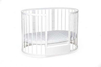 Ergonomic round baby mattress fitted perfectly inside the white KOTTO crib with open side.