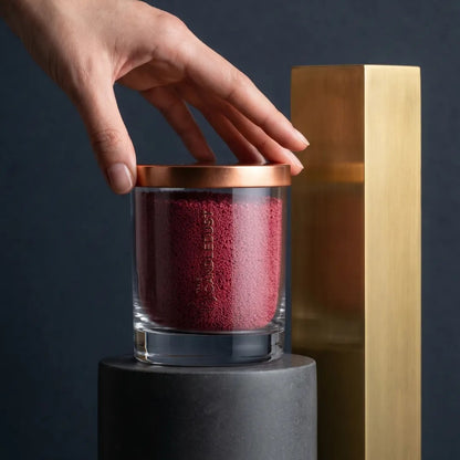 Woman's hand that touches a 160g Sangria Red unscented glass candle on an elegant spot