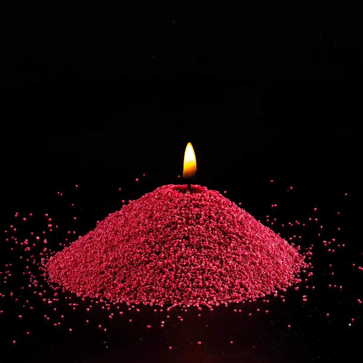 Burning Sangria pearled sand candle with a bright flame isolated on a dramatic black background