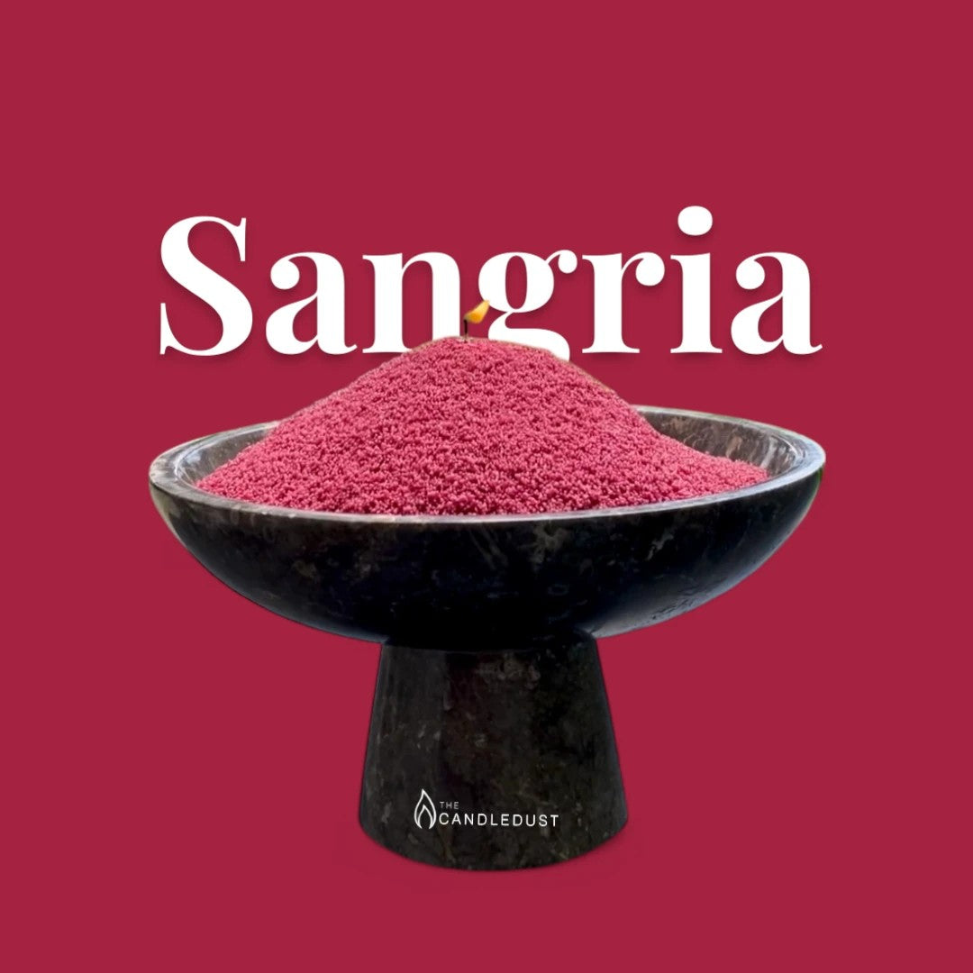 Sangria text on a matching rich sangria red background with a glass vase full of unlit pearled candle sand in the foreground
