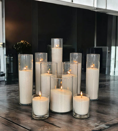 Glass vases of various heights filled with burning Silver pearled candle sand creating a glowing cluster