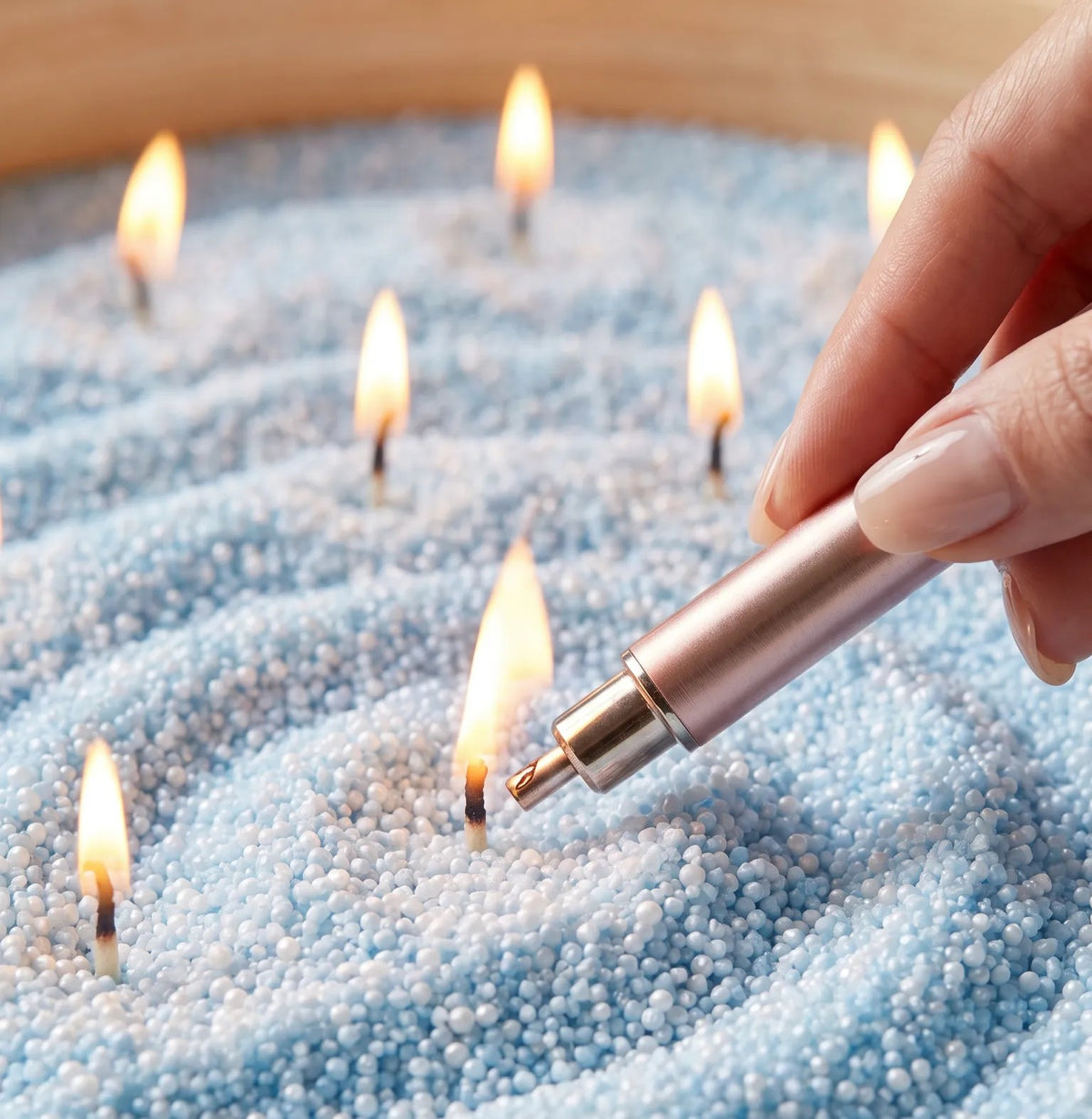Close-up of a woman's hand lighting the cotton wick of a Sky Blue pearled sand candle