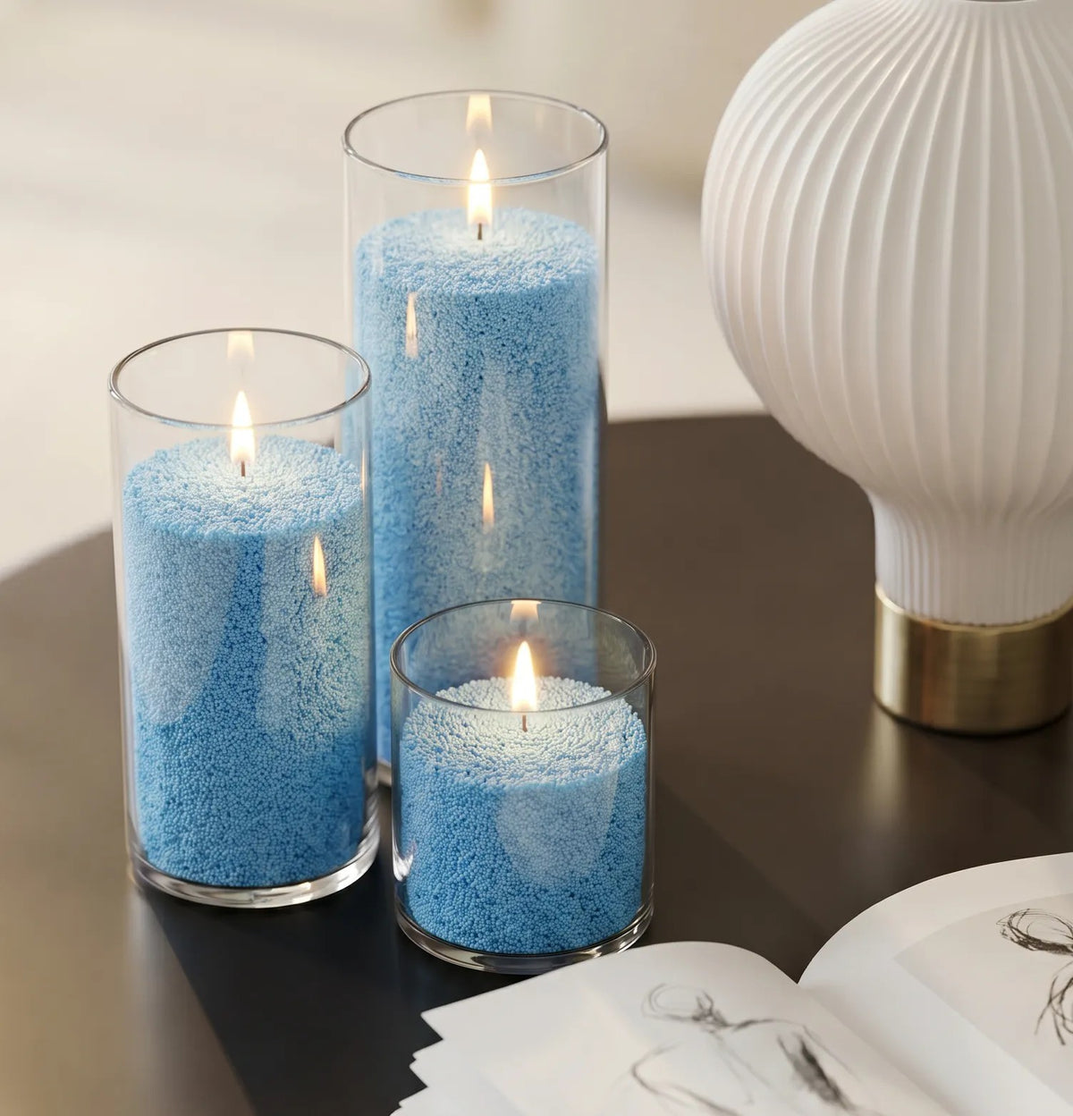 Three glass vases of various heights filled with burning Sky Blue pearled candle sand creating a glowing cluster