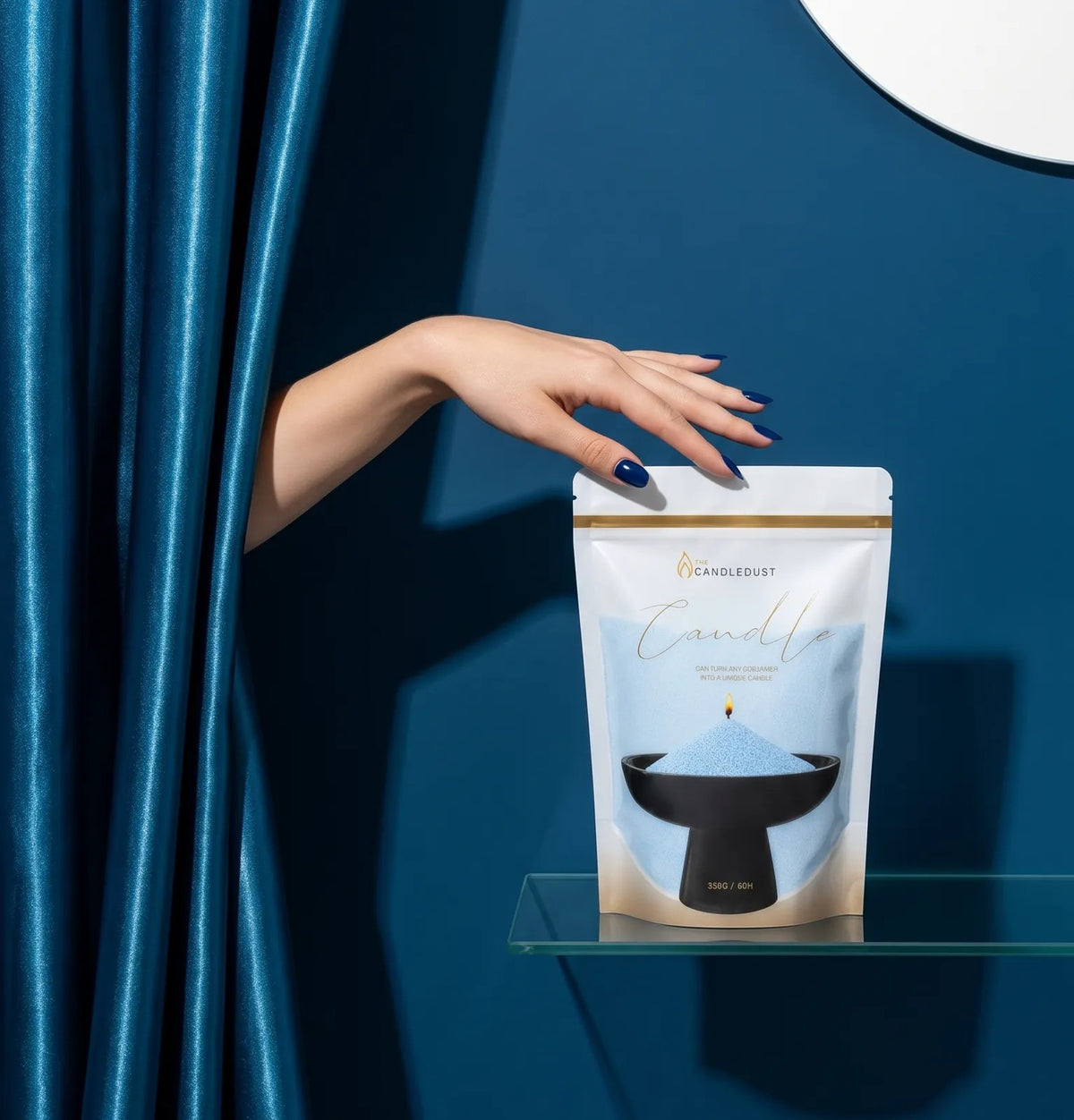 Woman's hand reaching from behind an elegant sky blue curtain to touch a 1kg pearled candle sand refill pouch on a glass shelf