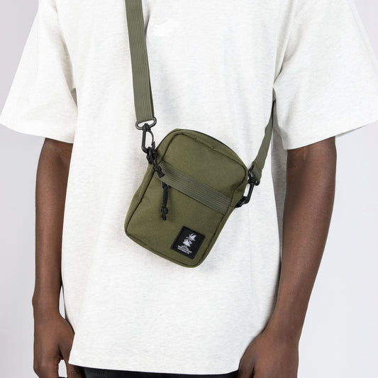 Model wearing the Moomin Snufkin travel cross body bag across the chest while summer outdoors