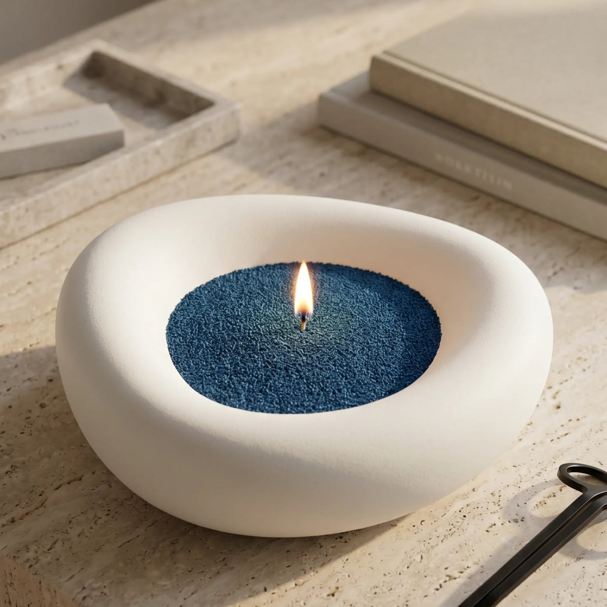 Modern artistic vase filled with Space Grey pearled candle sand and lit cotton wick resting on a refined stone countertop
