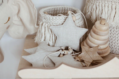 Close-up of the shimmering Sand Star Dust fabric stars resting on a smooth wooden stacking toy