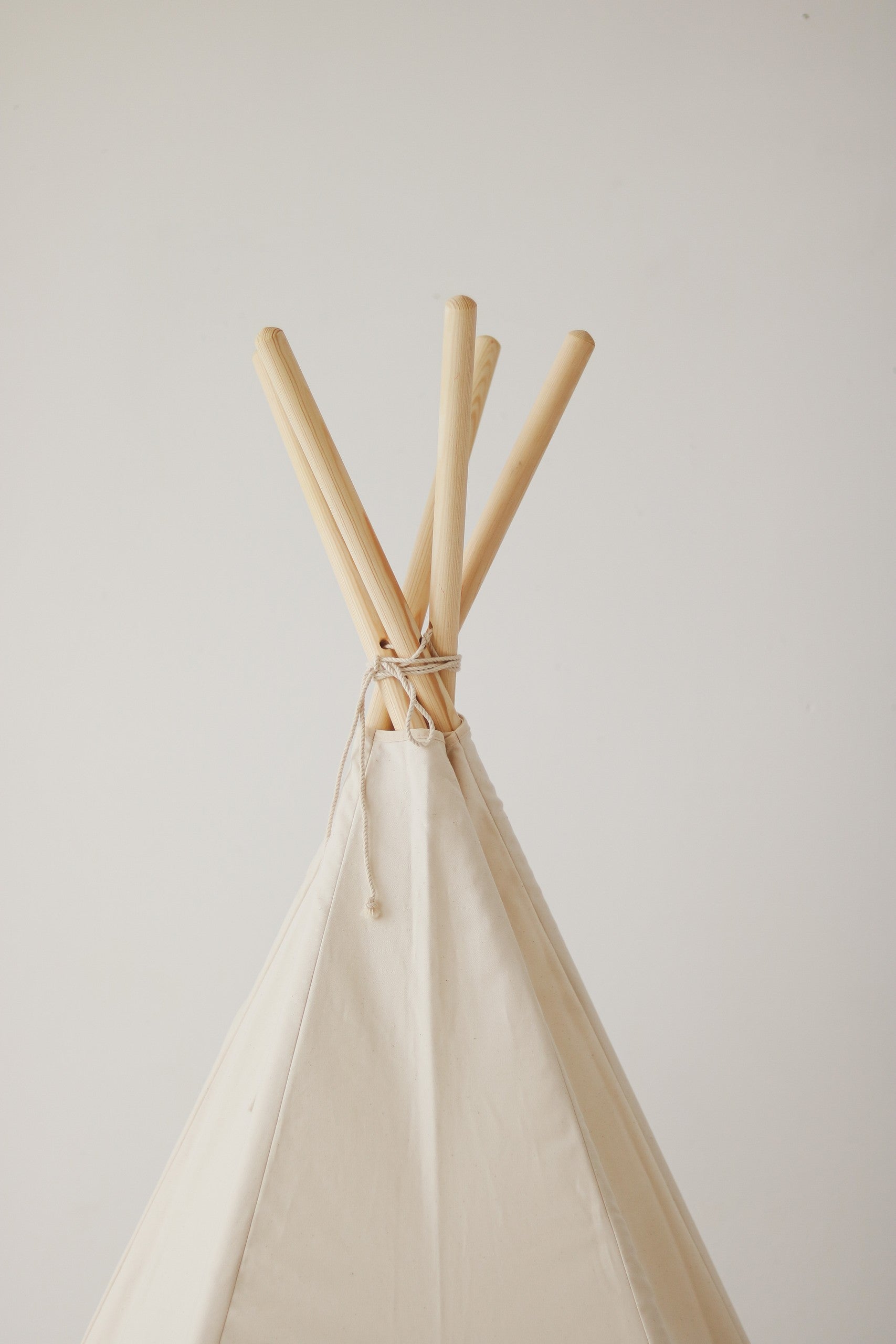 Close-up of the reinforced stitching and natural pine poles of the minimalist beige teepee