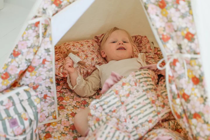 Cozy hideout: a close-up of a child resting safely inside a high-quality green canvas teepee tent made of OEKO-TEX certified cotton