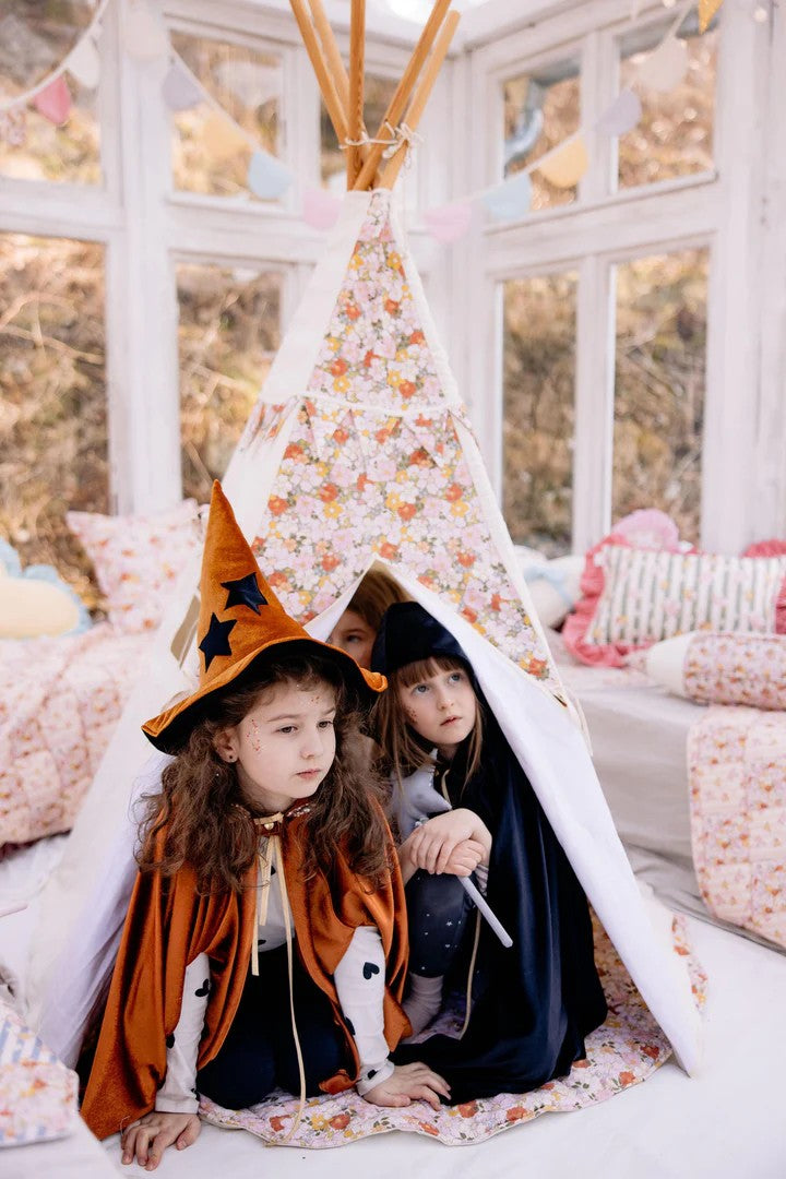 Cozy hideout: a close-up of three girls sharing secrets and laughing safely inside a high-quality green canvas teepee tent made of OEKO-TEX certified cotton