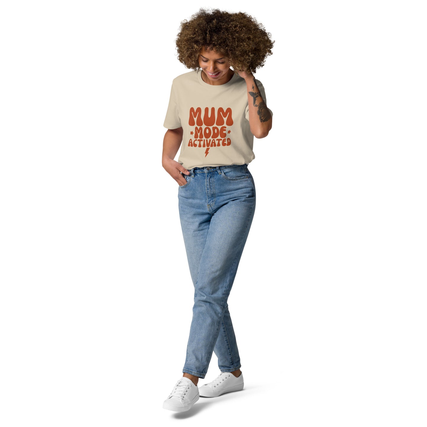 "A happy woman smiling while wearing a sand-colored organic cotton t-shirt with the retro terracotta MUM MODE ACTIVATED design.