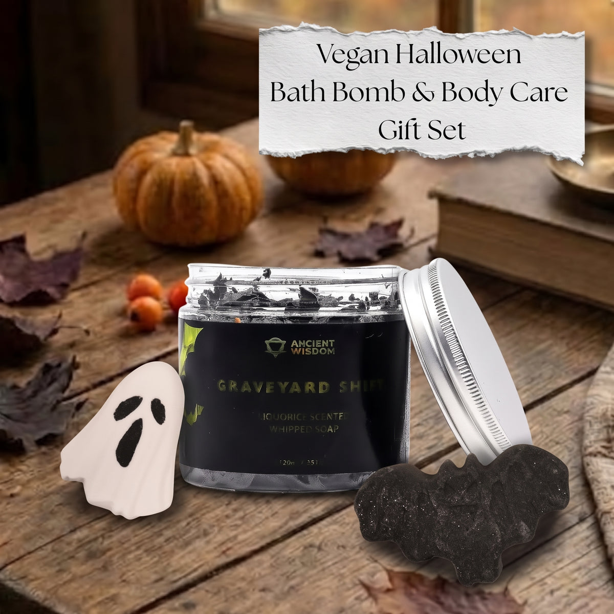Vegan Halloween Spooky Classics gift set featuring a ghost bath bomb, a black bat bath bomb, and charcoal whipped soap on a cozy autumn table