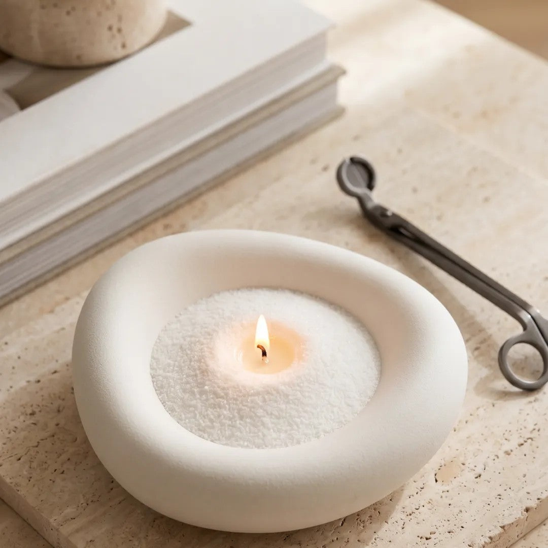 Elegant vase filled with White pearled candle sand and lit cotton wicks resting on a refined marble countertop