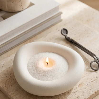 Elegant vase filled with White pearled candle sand and lit cotton wicks resting on a refined marble countertop